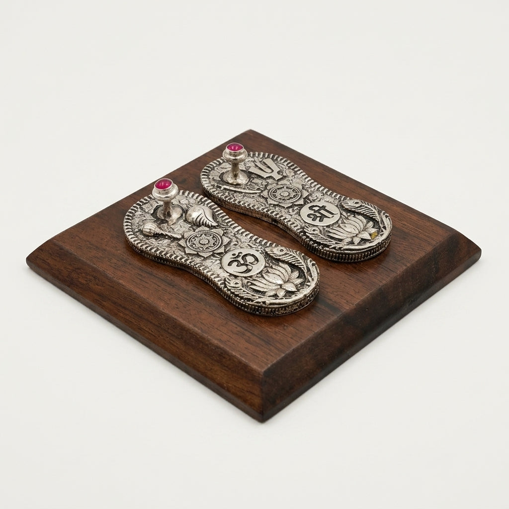 Vishnu Paduka pair on a wooden plank, silver plated finish with ruby accents