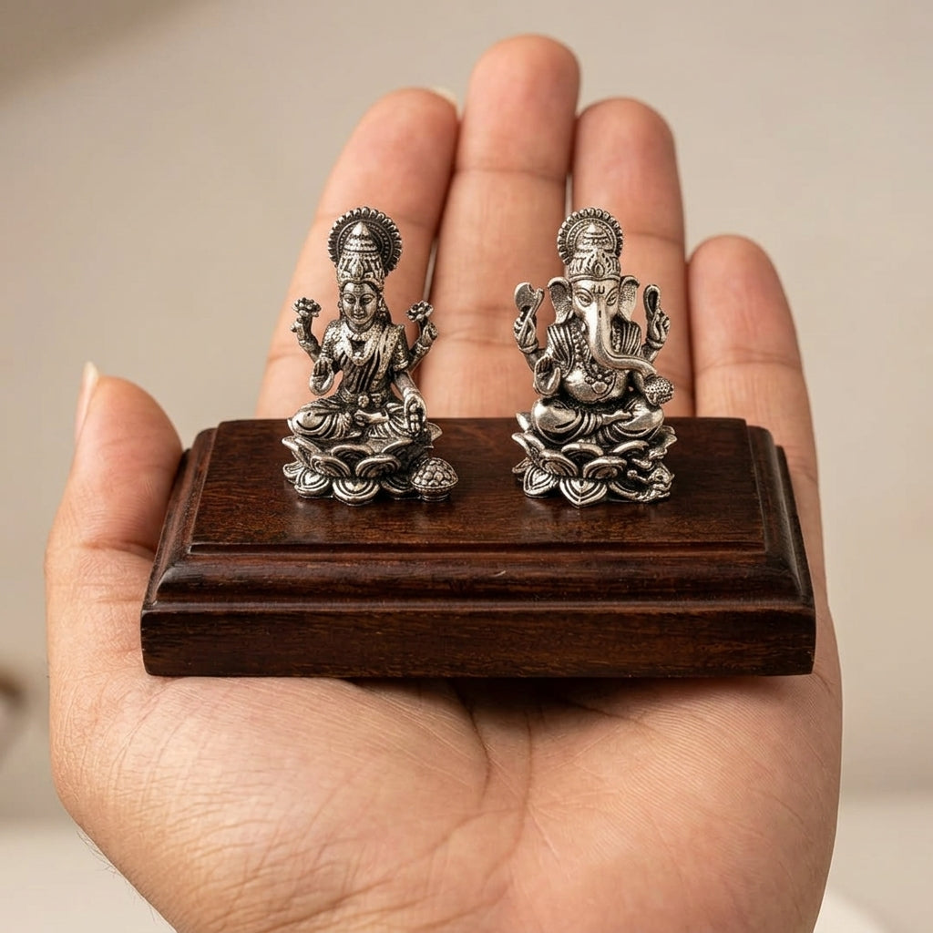Lakshmi Ganesh idol set held in hand to show scale, silver plated finish on wooden base