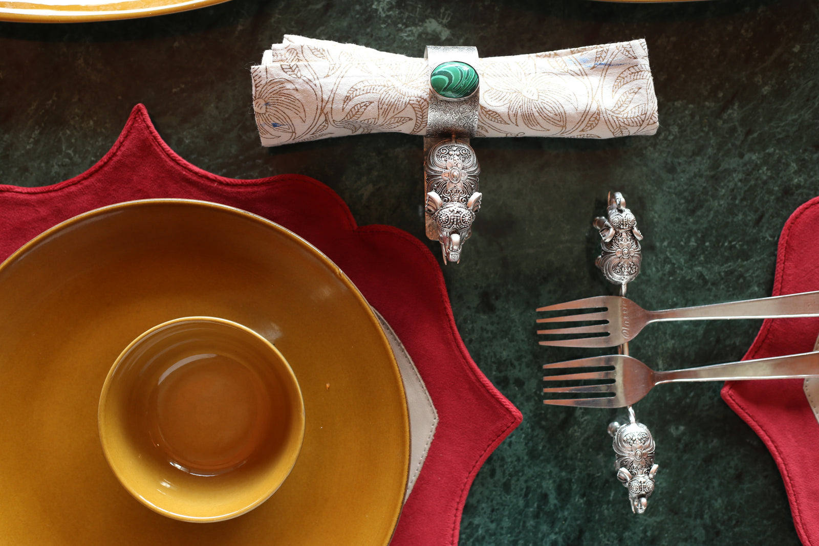 Silver-plated elephant napkin rings arranged beside a place setting.