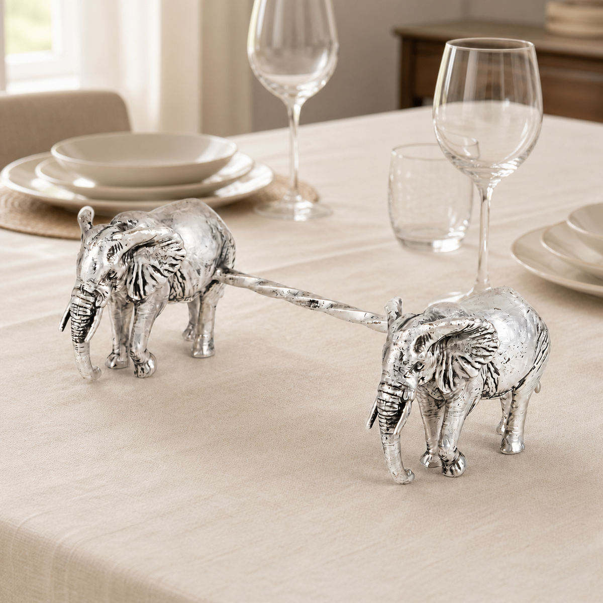Two silver-plated elephant spoon rests styled on an ivory dining table