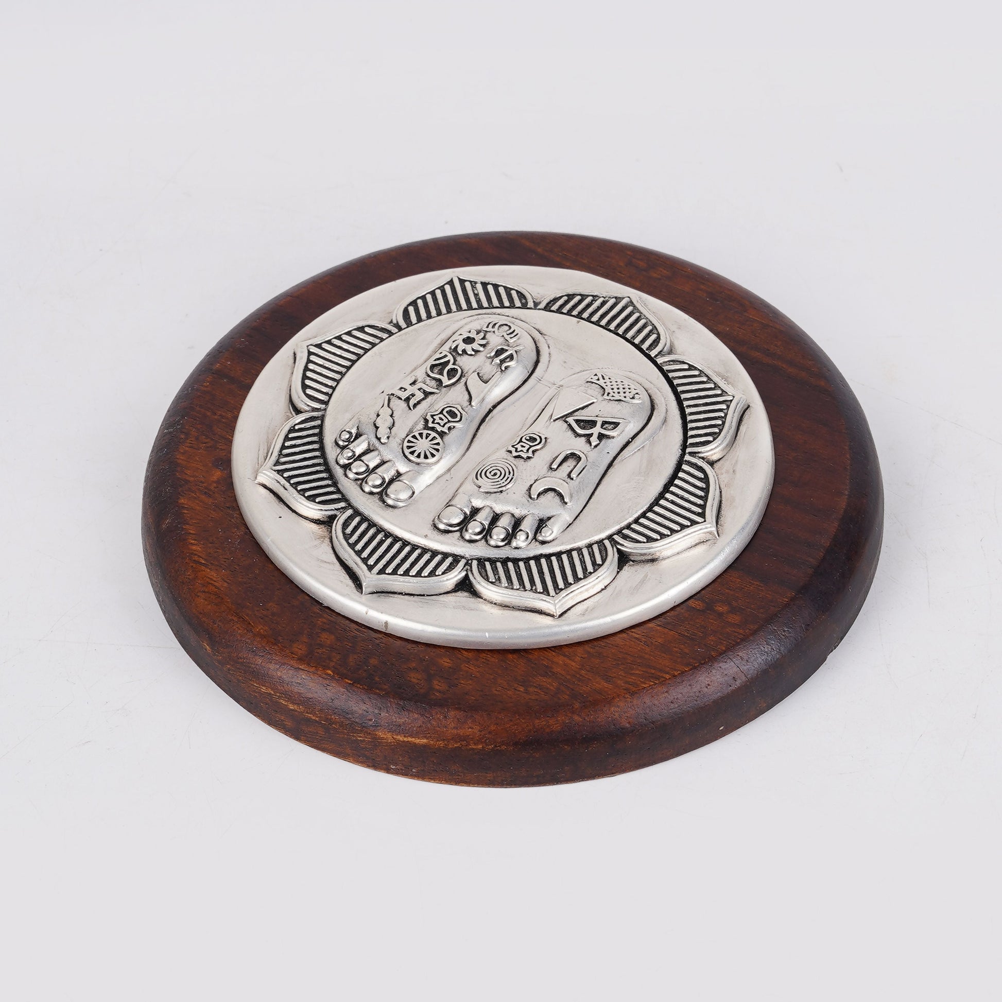 Lotus Lakshmi Charan silver charm on round wooden base, angled view