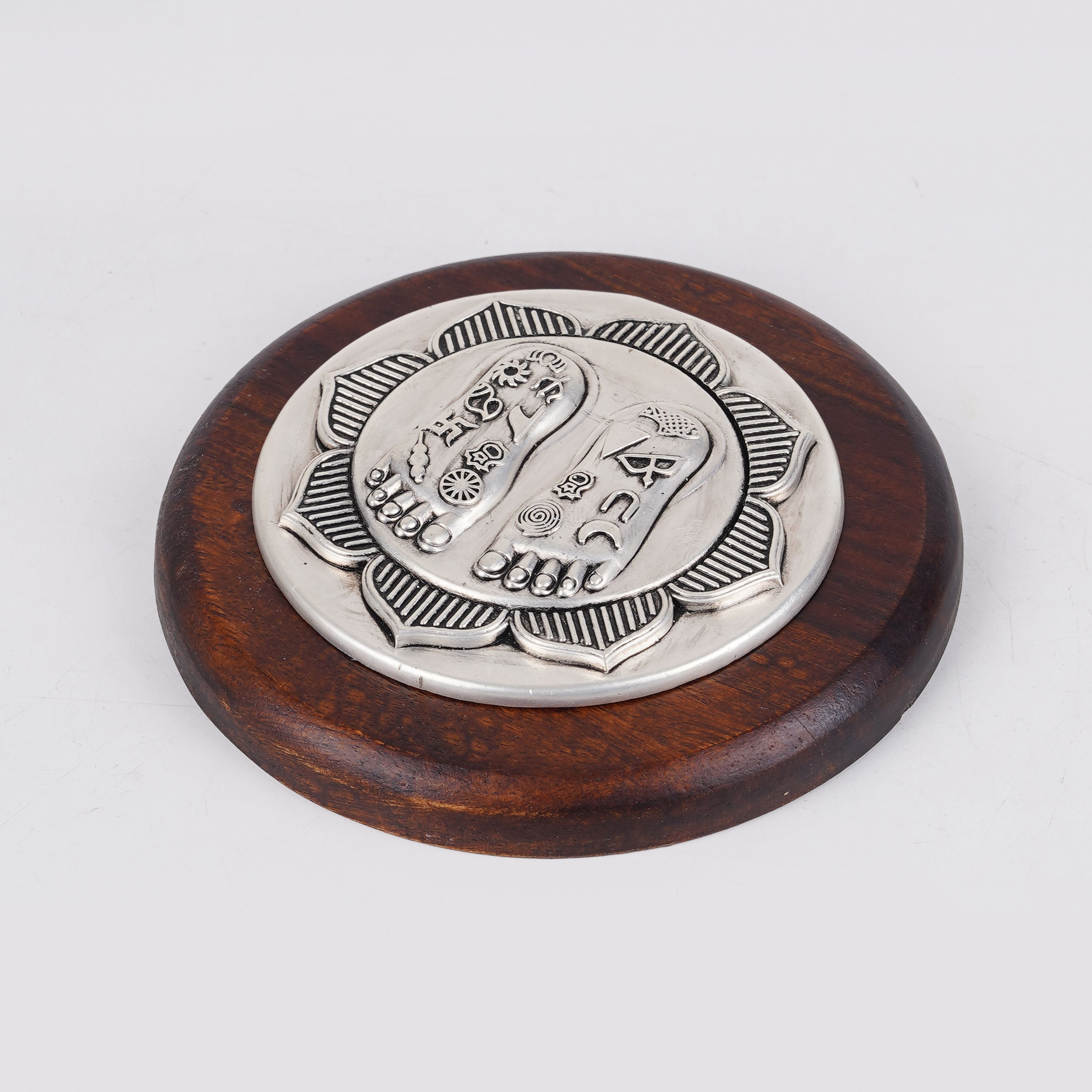 Lotus Lakshmi Charan silver charm on round wooden base, angled view