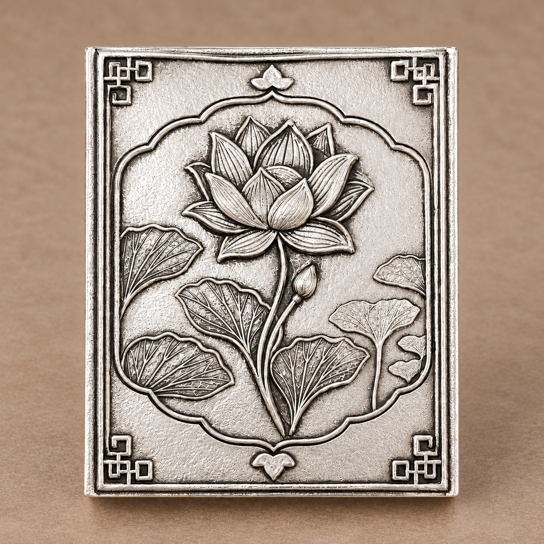 Silver-plated brass lotus matchbox cover standing upright, showing the hand-antiqued background