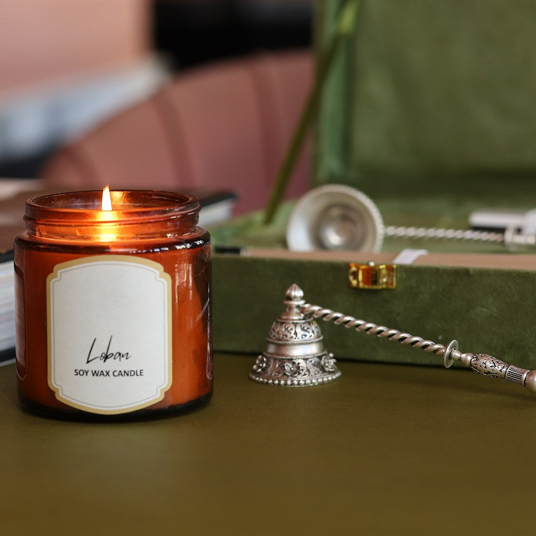 Silver bell-shaped candle snuffer beside a lit candle.