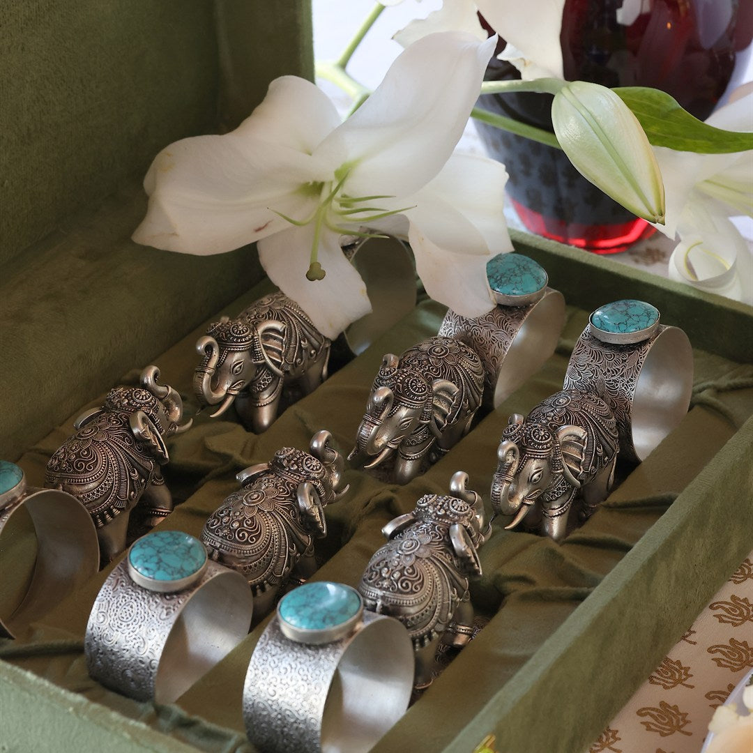 Pair of silver elephant napkin rings with folded napkins.